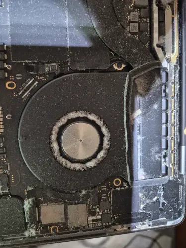 MacBook internal fan with dust buildup during cleaning and maintenance service